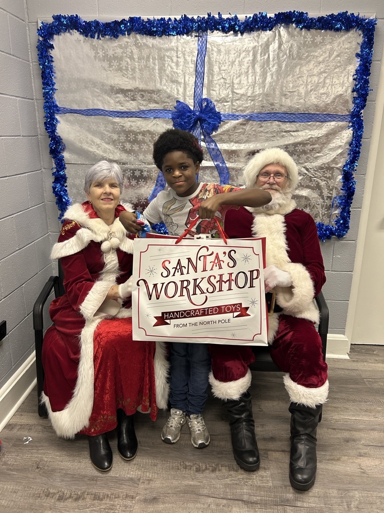 Boy receiving a christmas present from Santa and Mrs. Claus at the Lincoln Learners Christmas party