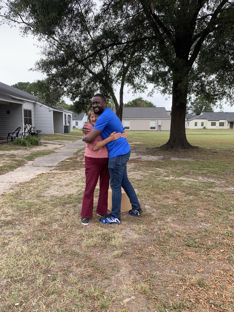 resident hugging staff member with food box